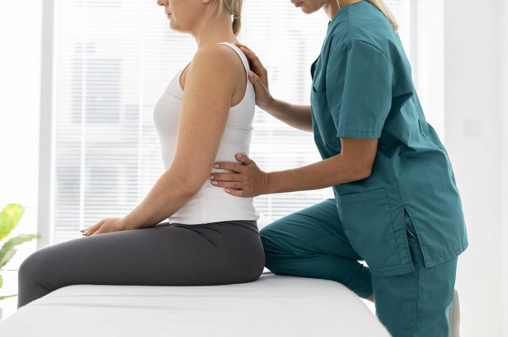 Young physiotherapist helping patient with back problems during a rehabilitation session.