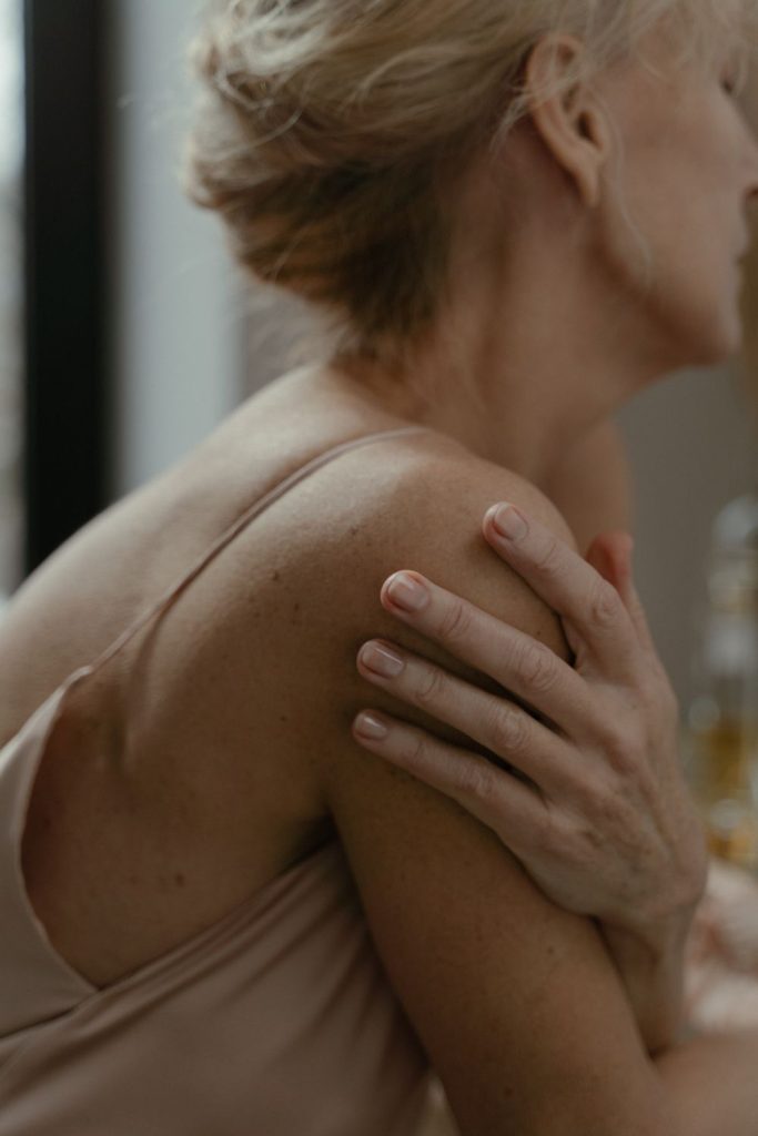 Older woman resting a hand on her shoulder indoors